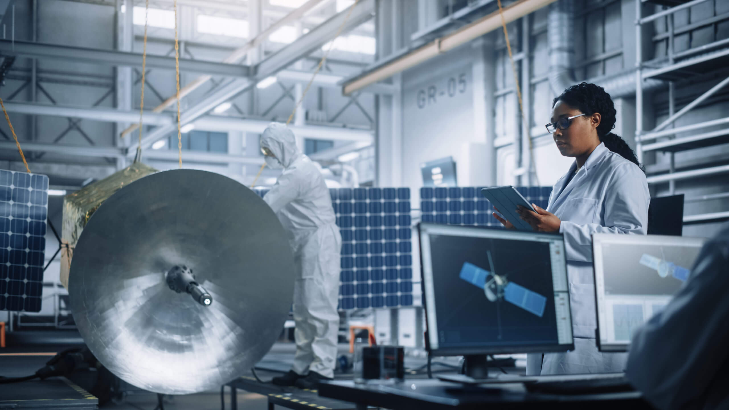 Female Engineer Uses Tablet Computer while Working on Satellite Construction in an Aerospace Agency Manufacturing Facility